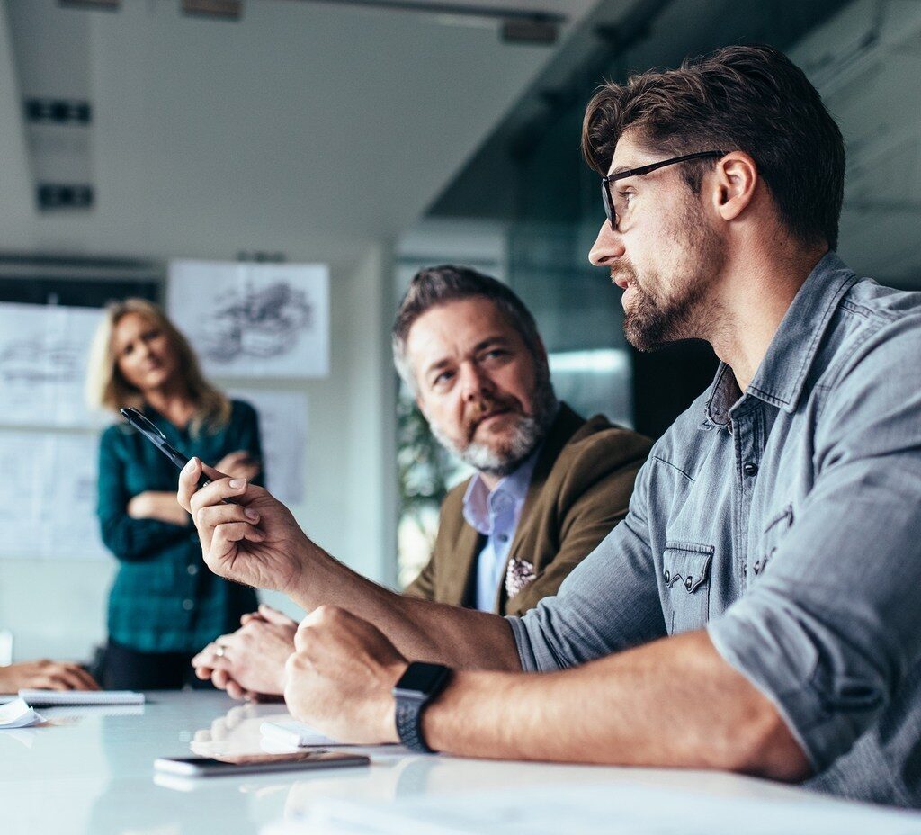 Young designer giving some new ideas about project to his partners in conference room. Business people discussing over new business project in office.